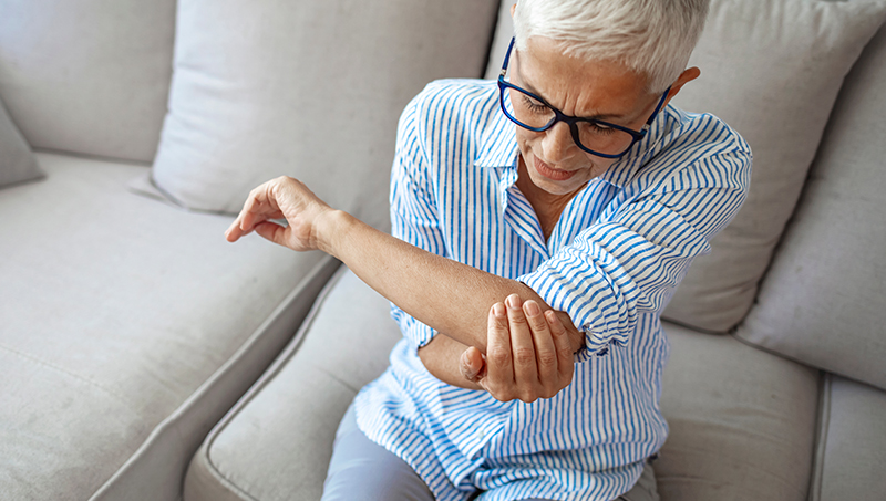 patient holding elbow in pain due to elbow bursitis